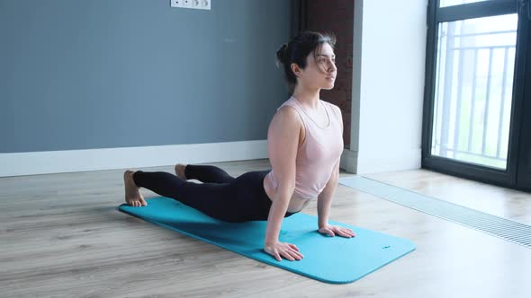 Young focused woman doing stretching exercises on a yoga mat in sportswear