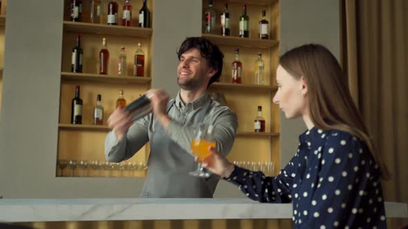 Man Bartender Working Preparing Cocktails at the Bar Talking to His Woman Client