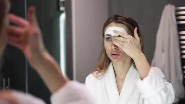 Portrait of a Woman in Bathrobe Putting White Mask for Moisturizing Using Fingers