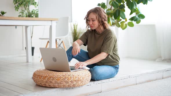 Woman Using Laptop Computer While Sitting Floor at Home Interior