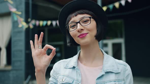 Slow Motion of Young Lady Showing OK Gesture Outside Smiling Looking at Camera