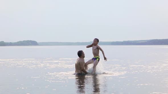 Father and Son are Having Fun and Splashing in the Water