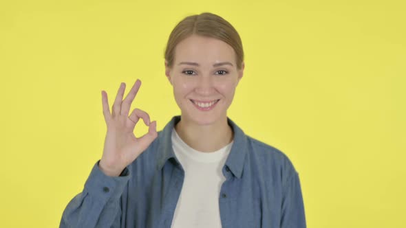 Young Woman Showing Okay Sign on Yellow Background