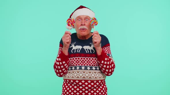 Grandfather in Christmas Sweater Holding Candy Striped Lollipops Hiding Behind Them Fooling Around