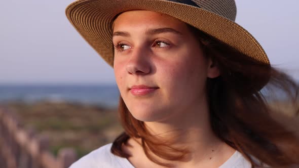 Teen girl in straw hat walking by the sea