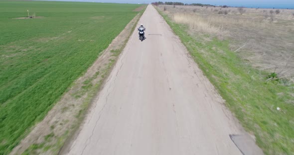 4K aerial drone shot of biker rides a motorcycle on the old road