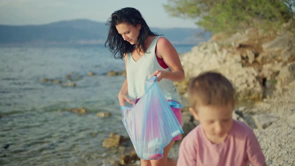 Mom and Little Son Clean the Beach