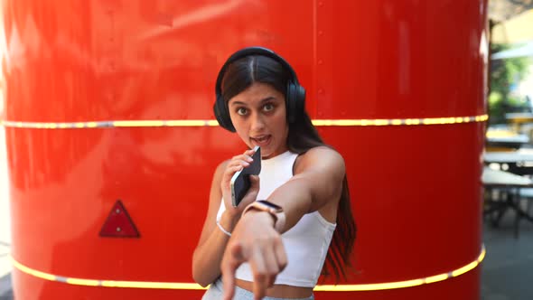 Young Woman Dancing in Headphones on the Street