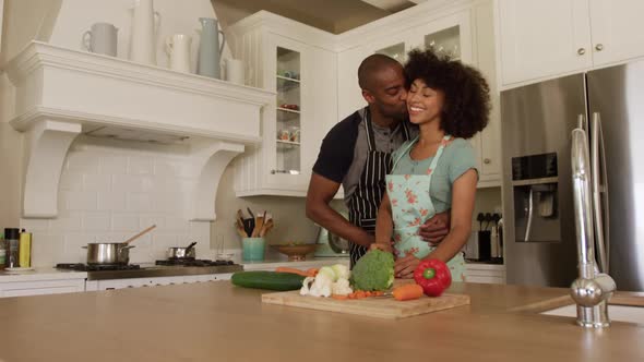 Happy mixed race couple cooking and dancing in their kitchen