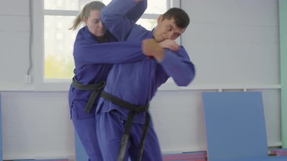 Male Jujutsu Athlete Doing Hip Throw during Fight with Female Partner