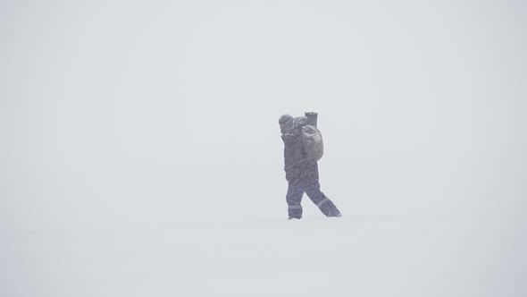 A Warmly Dressed Man Walks in a Heavy Snowfall