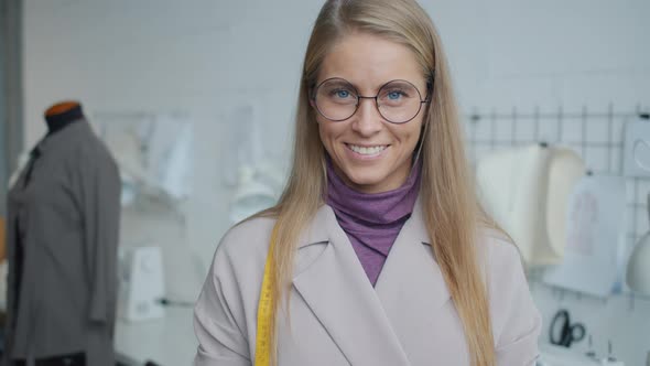 Portrait of Attractive Young Blonde Seamstress Standing in Modern Studio Smiling Looking at Camera