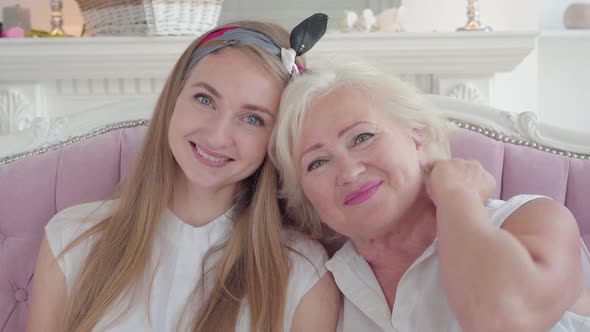 Close-up Portrait of Happy Caucasian Young and Senior Women Looking at Camera and Smiling. Beautiful