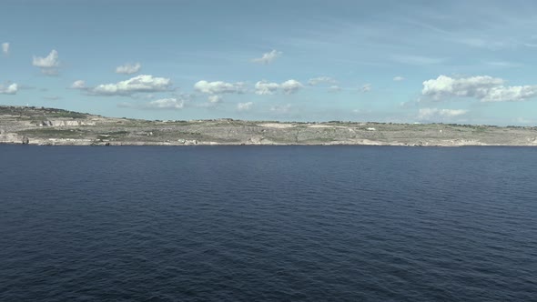 Slow aerial flight over the Mediterranean sea towards the coastal village of Ghar Lapsi on the Islan