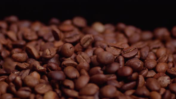 Close up shot of falling coffee bean grains in slow motion and black background.