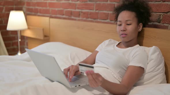 African Woman with Successful Online Payment on Laptop in Bed