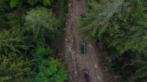 Aerial View of ATV Team Driving Through the Forest in the Mountains