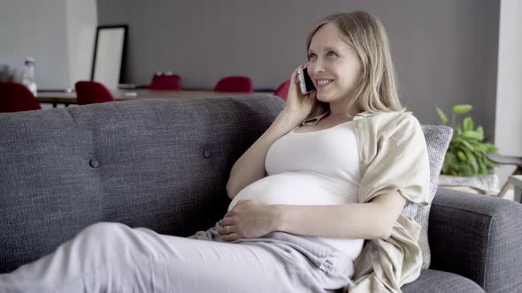 Smiling Pregnant Woman Talking on Smartphone