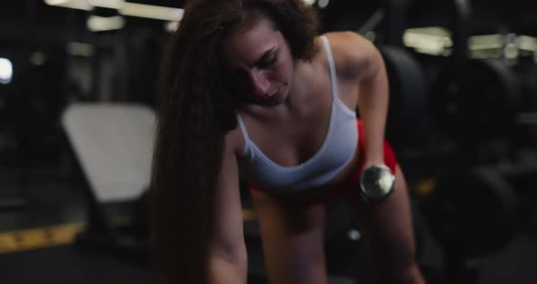 Fit Woman Doing Exercise with Dumbbell in the Gym