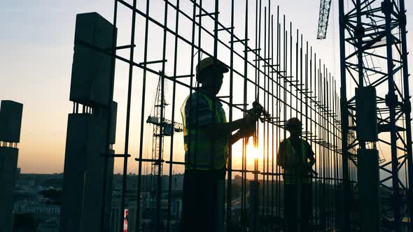 Male Engineers Work with Metal Construction on a Site.