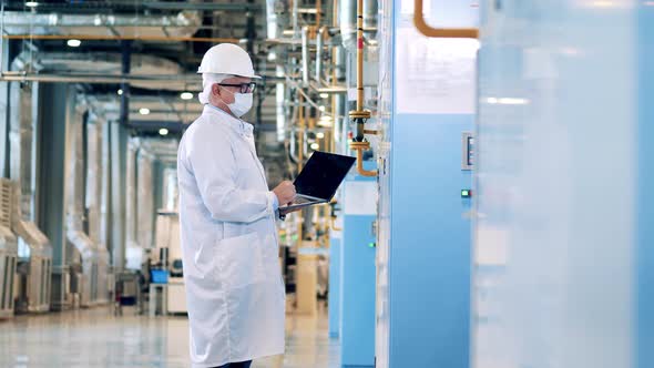 Male Factory Inspector with a Laptop is Operating Control Panels