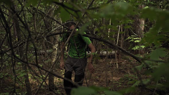 A Young Caucasian Man Makes His Way Through the Forest with a Backpack