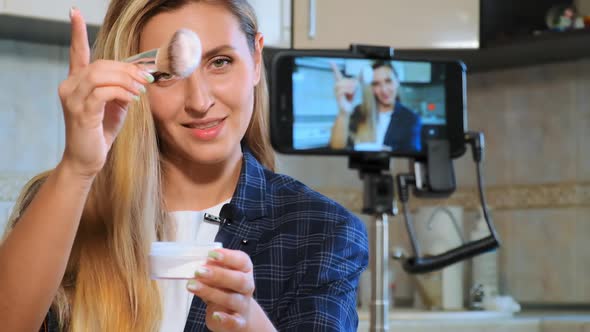 Long Haired Blogger Shakes Brush with Powder Over Container