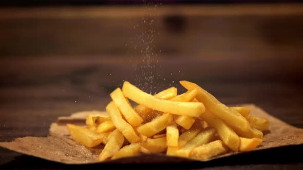 Super Slow Motion on the French Fries on Paper Pour Salt