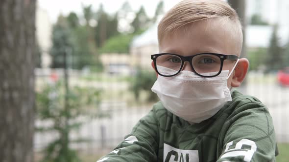 A boy in a protective mask stands near the house.