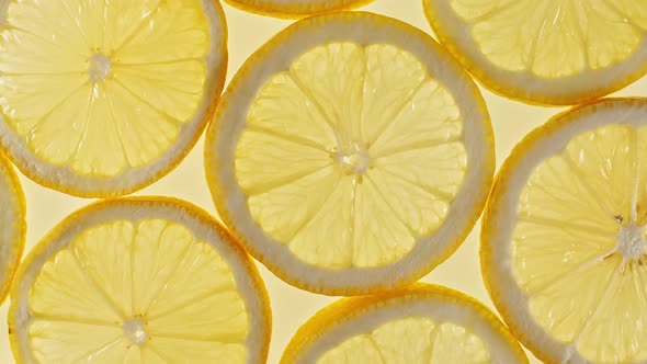 Slow Motion of Fresh Lemons Slices on Yellow Background