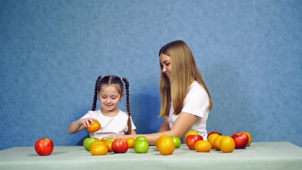 Girls with fruit on table. Beautiful woman and small girl with healthy food