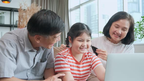 grand mother grandfather teach little child granddaughter using laptop sit on sofa, happy relation