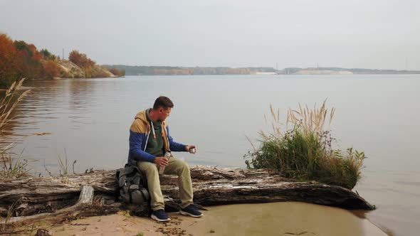 A Mature Man Tourist Traveler with a Backpack Walks in the Autumn Forest Near the River