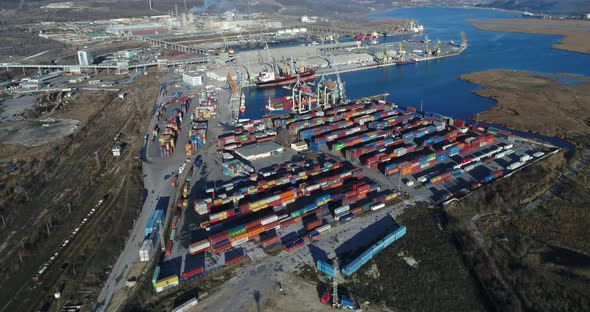 4K Aerial drone view of port container terminal. Industrial cargo harbor with ships and cranes.