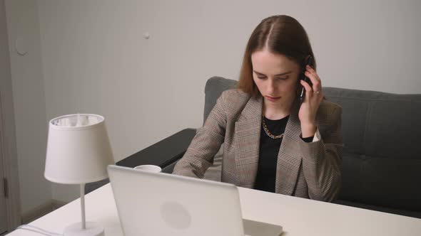 Young Businesswoman Talking on Phone Using Laptop Sit at Home Office Desk
