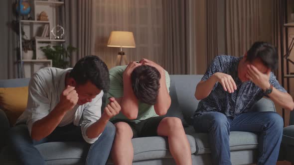 Three Asian Males Cheering And Watching Football Game On Tv And Disappointed At Home