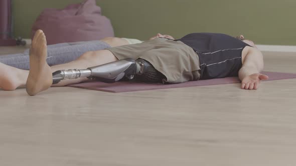 Man with Prosthetic Leg Relaxing on Mat in Yoga Studio