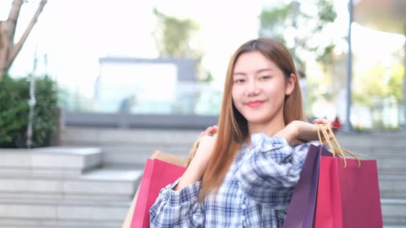 Smiling young Asian woman with shopping colour bags