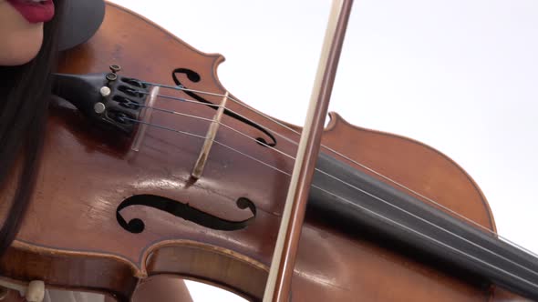 Woman Is Playing the Violin on White Background Near To Colleague. Close Up of Bow and Strings