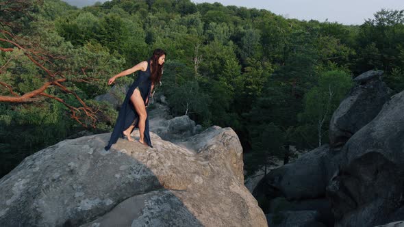 Woman Walks Along the Edge of a Cliff and Looks at the Sun