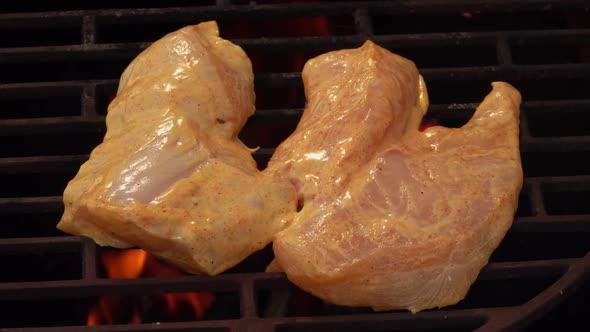Raw Marinated Chicken Fillet is Frying on the Grill Grid Above the Flames