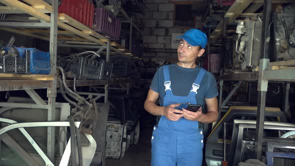 employee of auto disassembly, completes or checks car parts from tablet computer