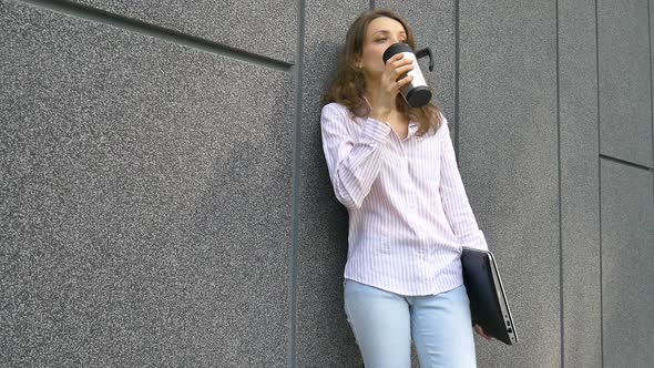 Female Portrait of Young Woman with Silver Laptop and Cup of Coffee Waiting for a Meeting Near Dark