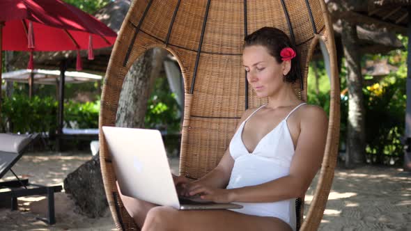 Female Freelancer Working Remotely in a Cocoon Chair at the Beach