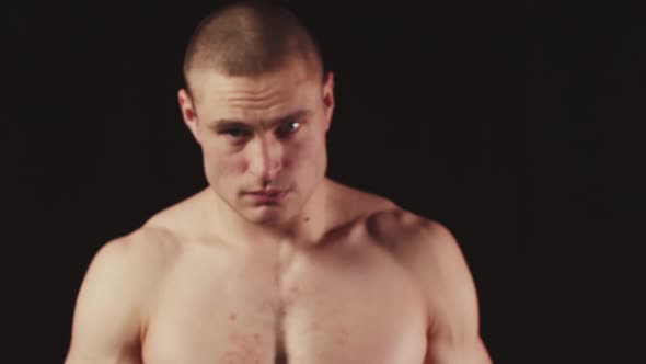 A Young Sports Man Looks Into the Camera While in a Black Studio