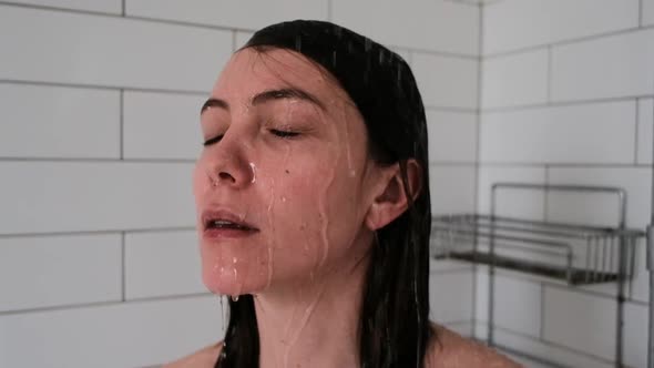 Pretty Brunette Woman with Closed Eyes Stands Under Water Jets in Shower Unit