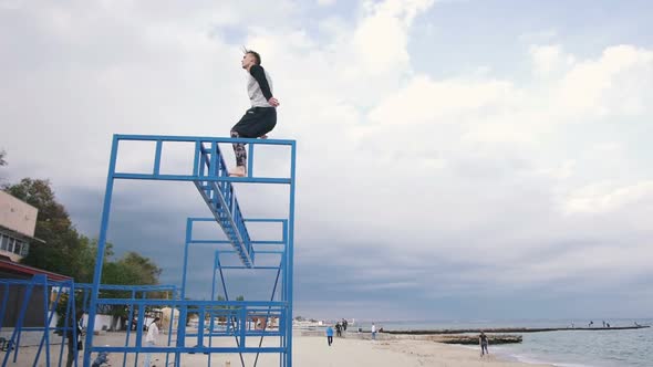 Young Man Doing Backflip Parkour Trick on the Beach Near the Sea