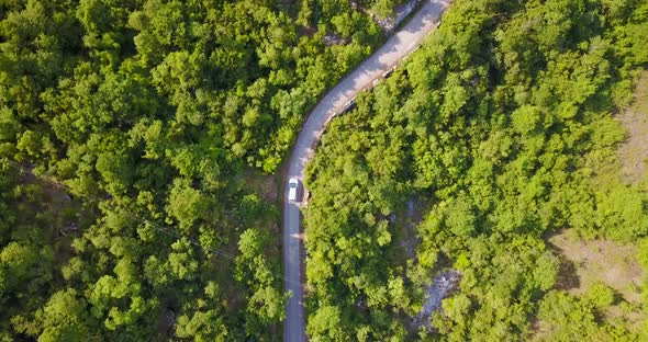 Aerial drone view of a minivan car vehicle driving on a rural road