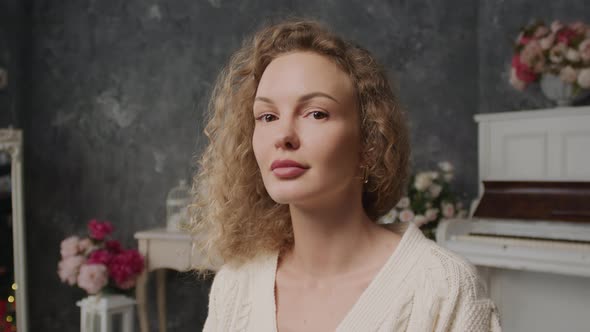 Handheld Portrait of a Curly Blond Caucasian Woman Looking at Camera Indoors