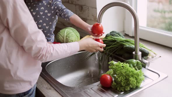 Close Up View of Young Beautiful Caucasian Mother and Her Cute Little Daughter Washing Vegetables